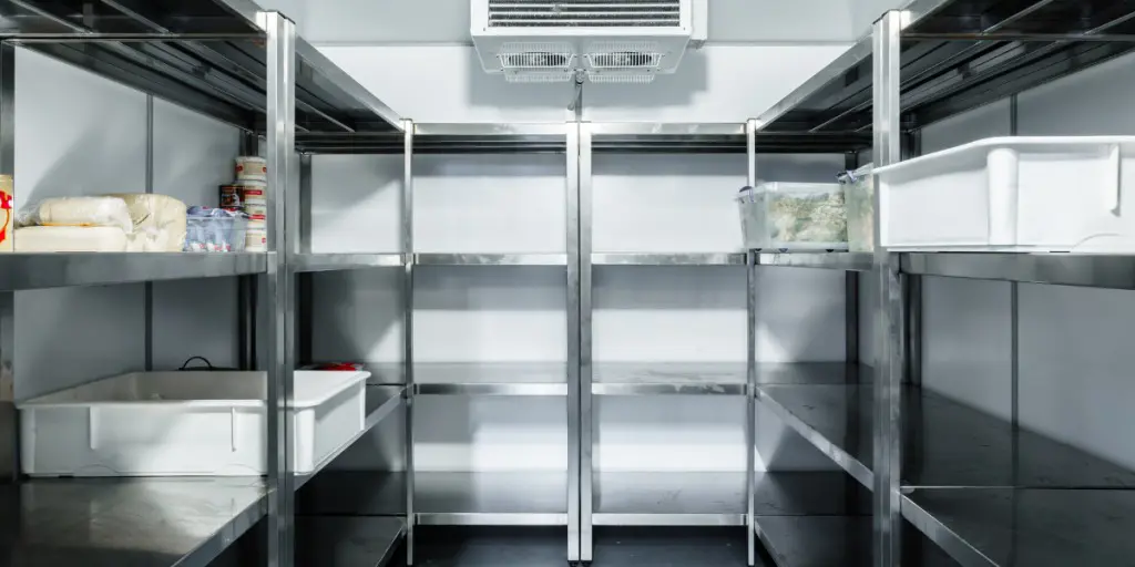 A walk-in refrigerator with stainless steel shelves holds food containers